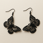 Détail des boucles papillon noires découpées motif ajouré finition mate