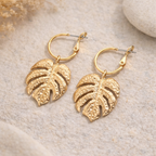 Détail créole dorée avec pendentif feuille monstera ajourée et texturée