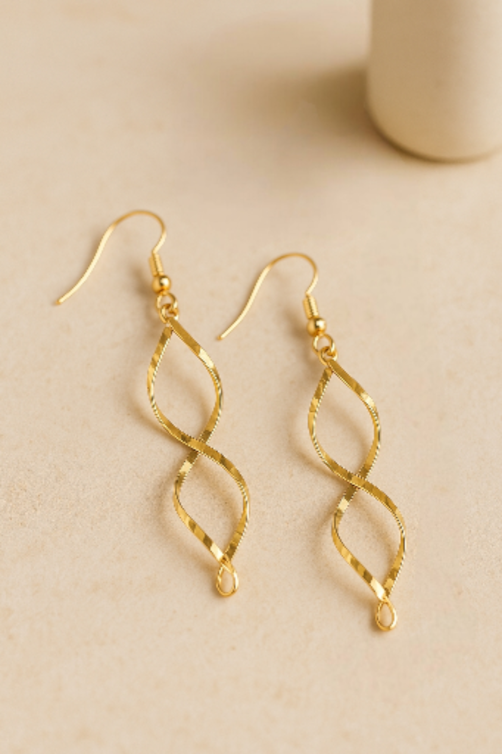 Détail boucles d oreilles pendantes dorées torsadées finition brillante