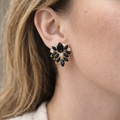 Boucles d'oreilles fleur noire dorée portées en puces avec cristaux