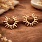 Détail des boucles dorées motif soleil avec rayons organiques et cercle ajouré