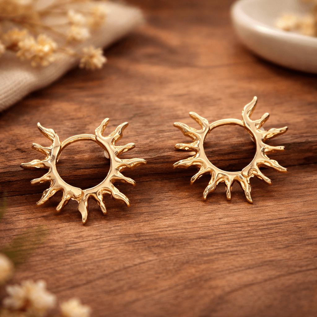 Détail des boucles dorées motif soleil avec rayons organiques et cercle ajouré