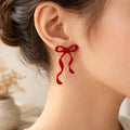 Boucles d'oreilles noeud rouge pendantes avec rubans ondulés