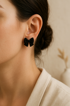 Boucles d'oreilles nœud noir puces portées sur lobe, finition mate