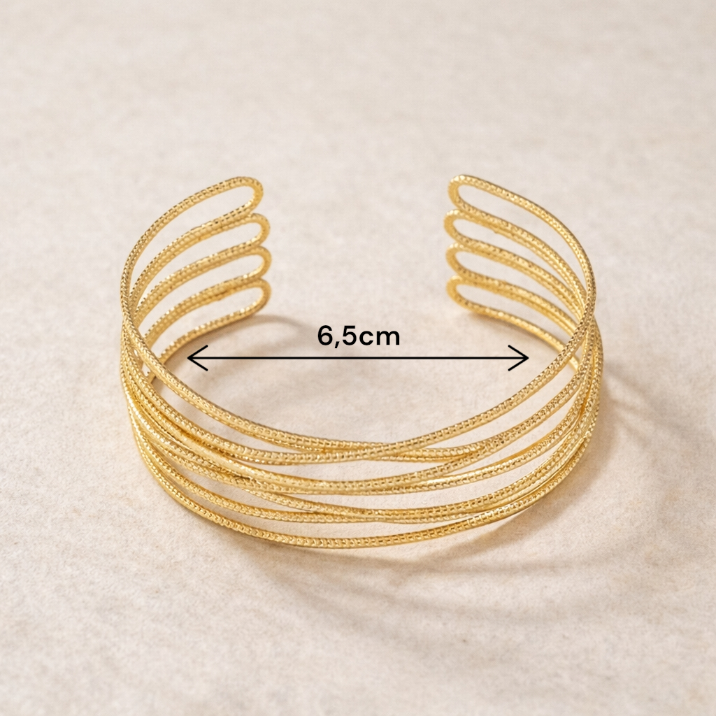 Bracelet manchette doré porté au poignet avec une tenue chic et moderne