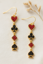 Détail boucle d’oreille dorée avec cœur rouge scintillant trèfle noir carreau rouge pique noir