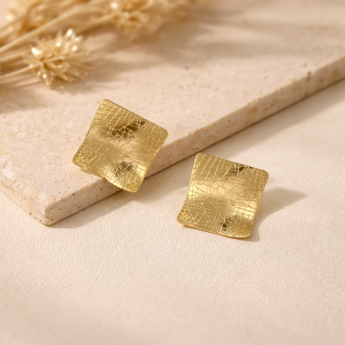 Détail texture craquelée sur boucles d’oreilles carrées finition dorée