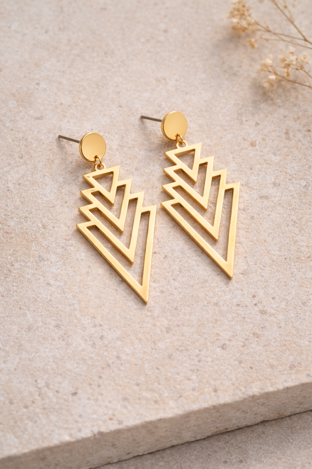 Détail des boucles dorées design graphique triangles ajourés