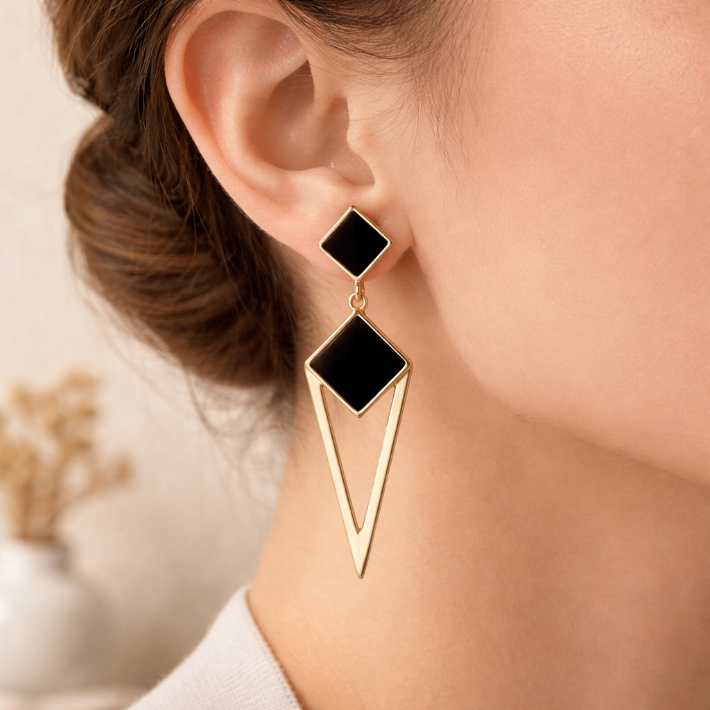 Boucles d’oreilles pendantes géométriques noir et doré portées à l’oreille