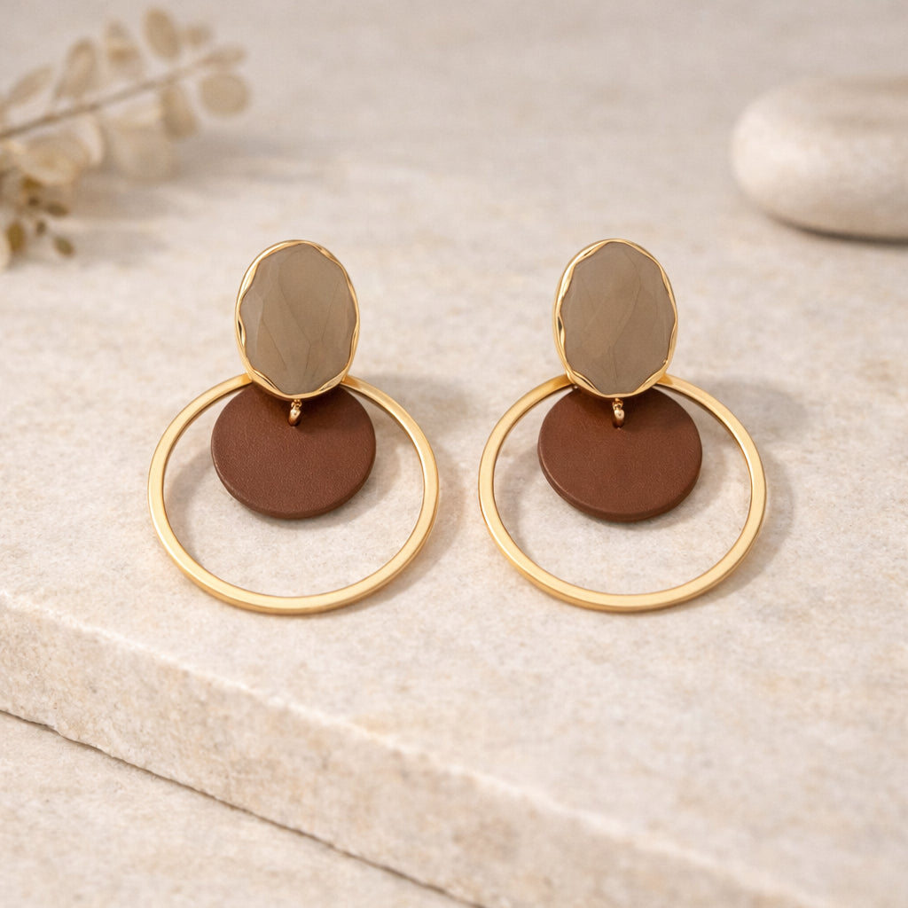 Détail des boucles d’oreilles : pastille ovale beige, disque brun mat et anneau doré
