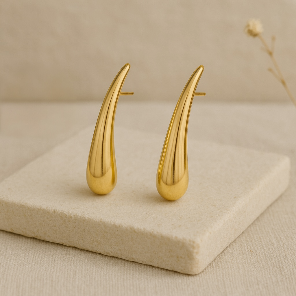 Détail boucles d’oreilles dorées forme goutte lisse allongée finition brillante